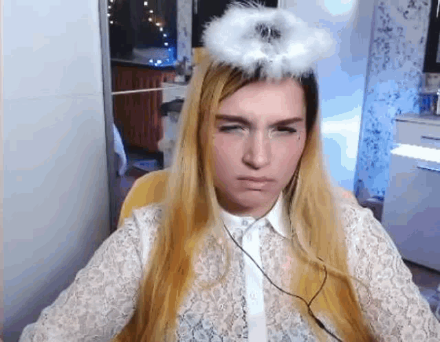 a woman wearing a white shirt and a white angel wing on her head is making a funny face .
