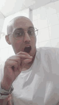 a bald man with glasses and a rainbow wristband looks at the camera