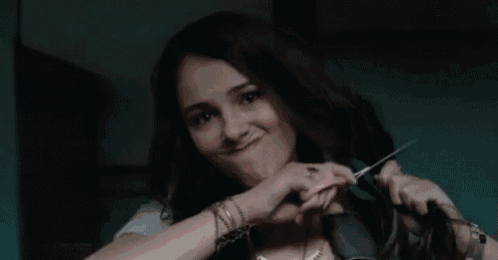 a woman is brushing her hair with a pink brush while making a funny face .