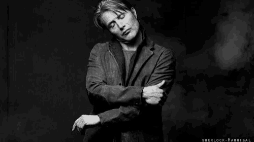 a black and white photo of a man standing with his arms crossed .