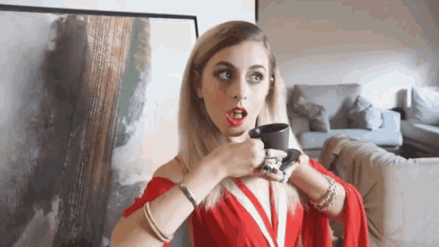 a woman in a red dress holds a cup of coffee