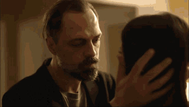a man with a beard is kissing a woman