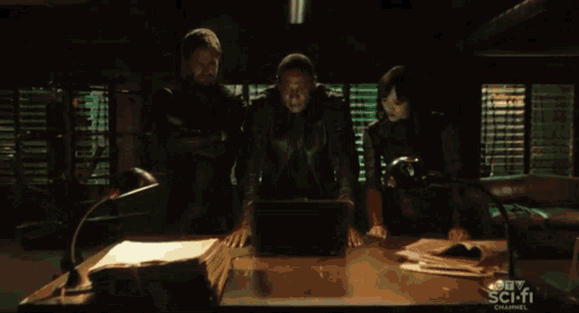 a group of people are looking at a laptop with a ctv scifi channel advertisement in the background