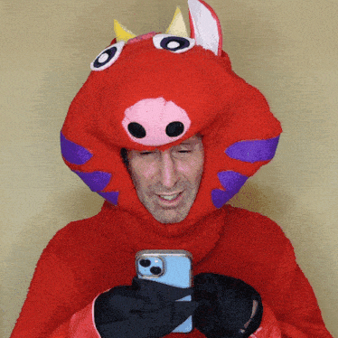 a man in a red pig costume is looking at his cell phone