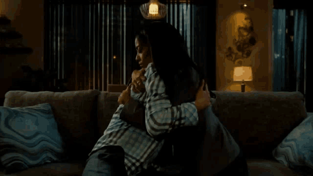 a man and a woman hugging on a couch in a living room