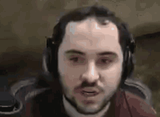 a man with a beard wearing headphones is sitting in a chair .