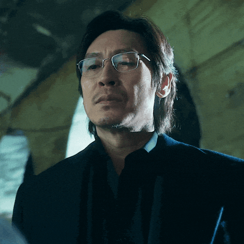 a close up of a man wearing glasses and a black suit