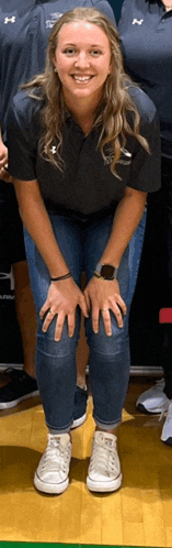 a woman in a black shirt and blue jeans is posing for a picture .