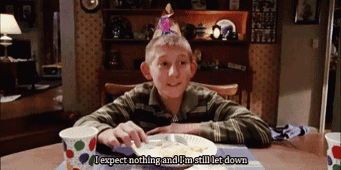 a young boy wearing a party hat is sitting at a table with a plate of food