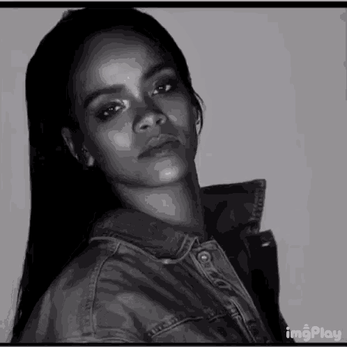 a black and white photo of a woman wearing a denim jacket looking at the camera .