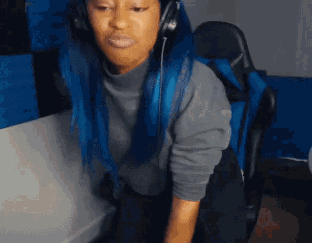 a woman with blue hair is wearing headphones and a grey shirt