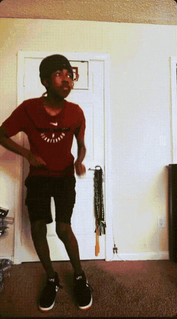 a young man wearing a red nike shirt is dancing in front of a door