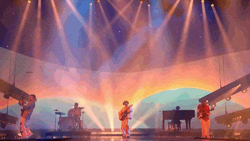a group of people are playing instruments on a stage with a sunset in the background