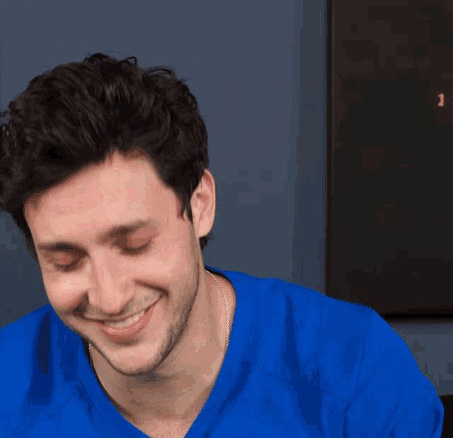 a man wearing a blue shirt is smiling with the letter j visible in the background