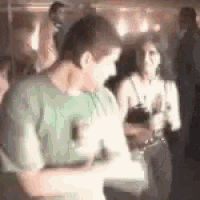 a man in a green shirt is dancing in a crowd