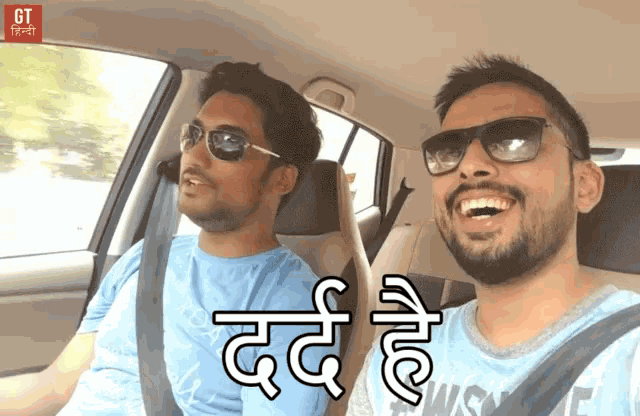 two men are laughing in a car with the word gt on the bottom