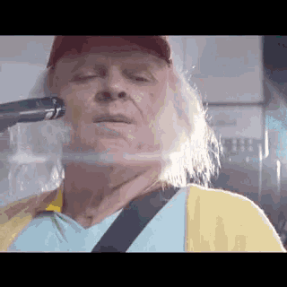 a man in a yellow shirt is holding a gun to his face .