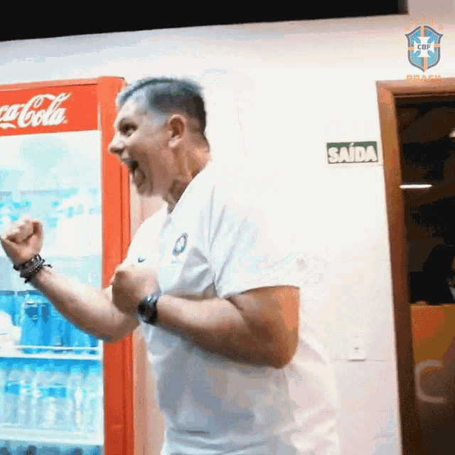 a man is standing in front of a coca cola cooler