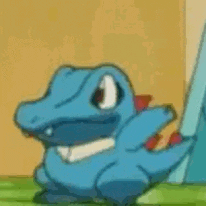 a blue dinosaur with a red tail is sitting on a grassy field .