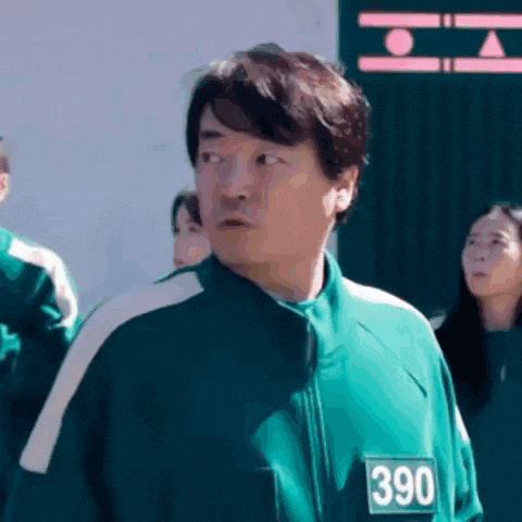 a man in a green tracksuit with the number 390 on it is standing in front of a group of people .