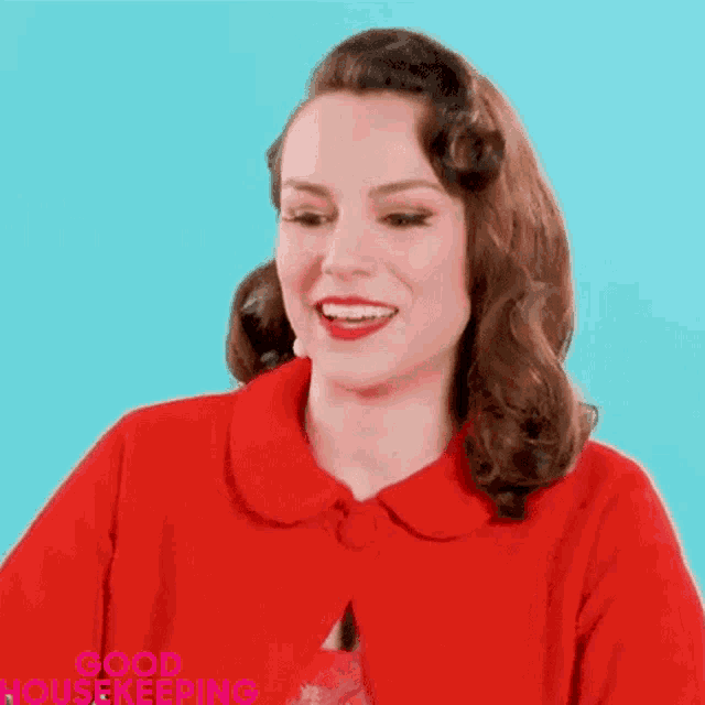 a woman is wearing a red jacket and smiling with the words good housekeeping behind her .