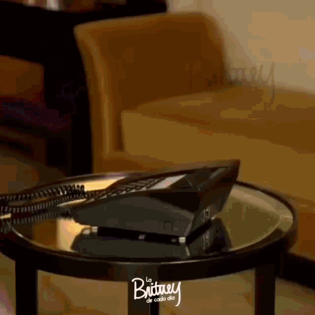 a phone sitting on a glass table with britney de cada dia written on the bottom