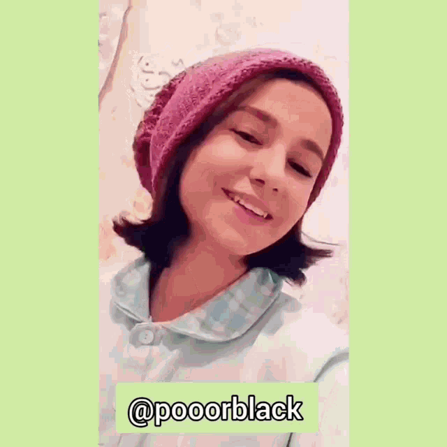 a girl wearing a pink hat and a blue shirt is smiling and making a funny face .