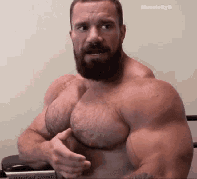 a shirtless man with a beard is standing in front of a ultrafast cross trainer