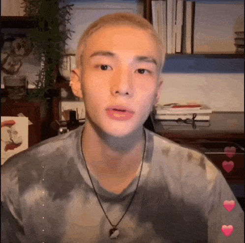 a young man wearing a tie dye shirt and a necklace looks at the camera .