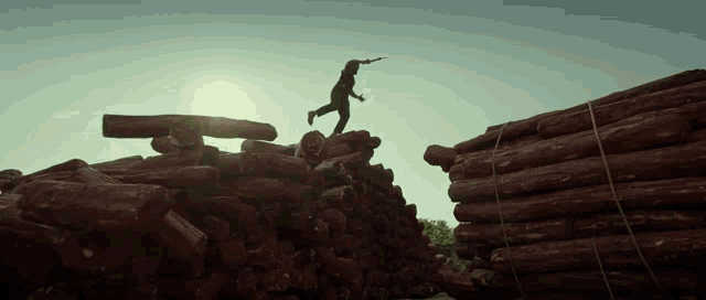 a man jumps over a pile of logs with a gun in his hand