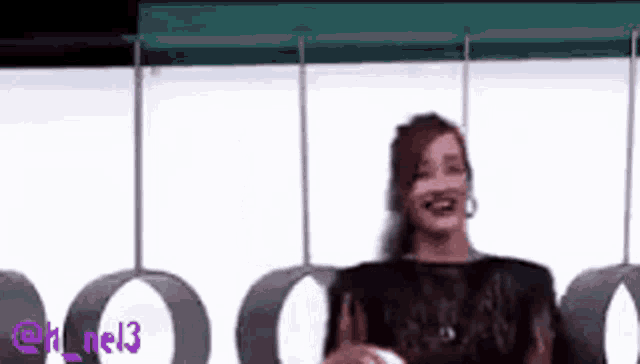 a woman is sitting on a swing and smiling while wearing a black dress .