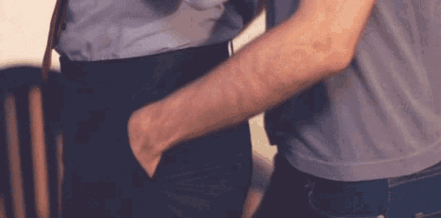 a man is holding another man 's hand in his pocket while standing next to each other .