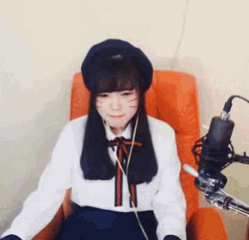 a girl wearing a beret and headphones is sitting in an orange chair in front of a microphone