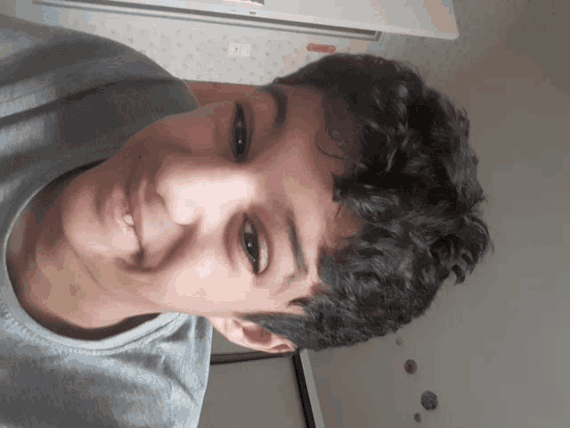 a young man with curly hair is smiling and looking at the camera