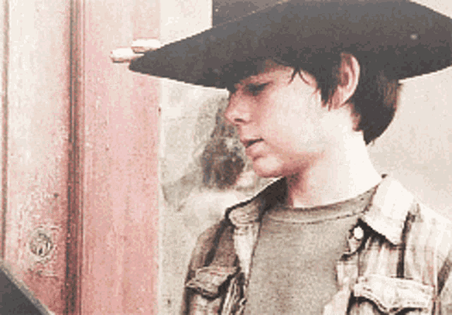 a young boy wearing a cowboy hat is looking down