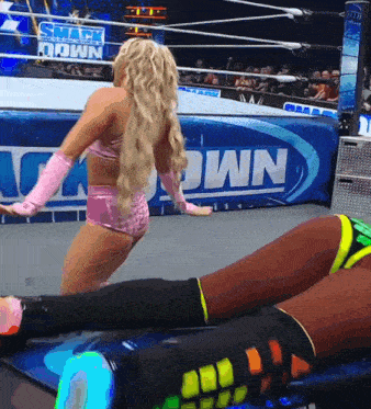 a female wrestler is standing in front of a smack down sign