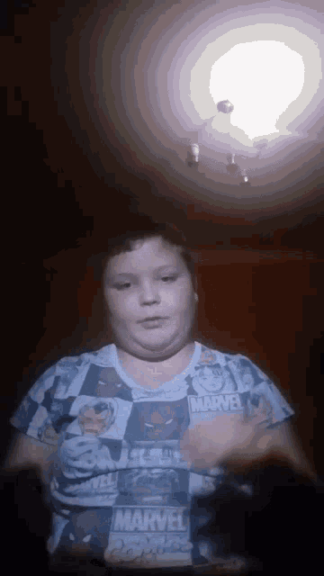 a boy is wearing a marvel shirt and looking at the camera
