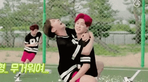 two boys are playing soccer on a field and one of them is carrying the other on his back .