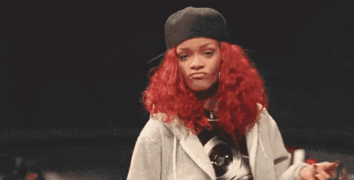 a woman with red hair is wearing a hat and a hoodie and giving the middle finger .