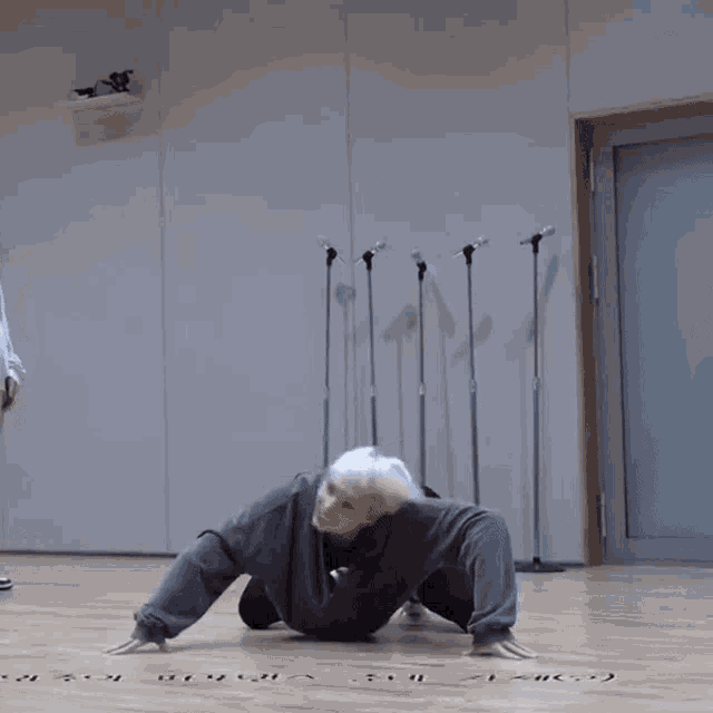 a man with white hair is crawling on the floor in a room with korean writing