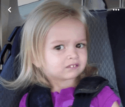 a little girl with blonde hair is wearing a purple shirt and a seat belt .