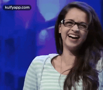 a woman wearing glasses and a striped shirt is laughing with her mouth open .