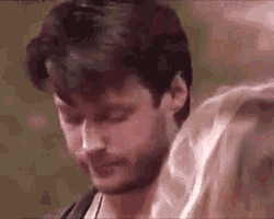 a man with a beard and a woman with blonde hair are standing next to each other with their eyes closed .