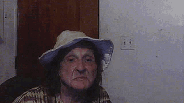 a man wearing a hat and a plaid shirt is sitting in front of a door .