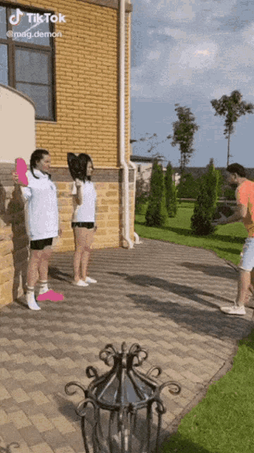 a tiktok video of people playing frisbee with a brick house in the background