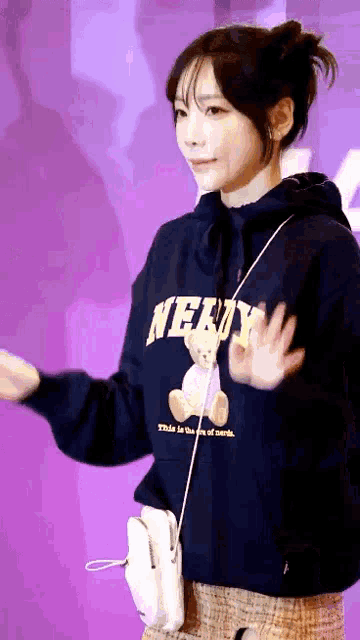 a girl wearing a nerdy hoodie is waving her hand