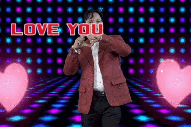 a man in a red jacket is making a heart shape with his hands and the words love you are above him