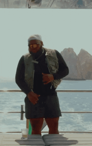 a man wearing sunglasses and a headband is standing on a deck overlooking the ocean