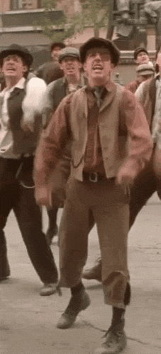 a group of men are standing on a sidewalk dancing