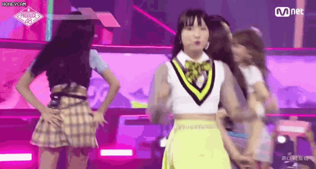 a group of girls are dancing on a stage in front of a mnet logo .